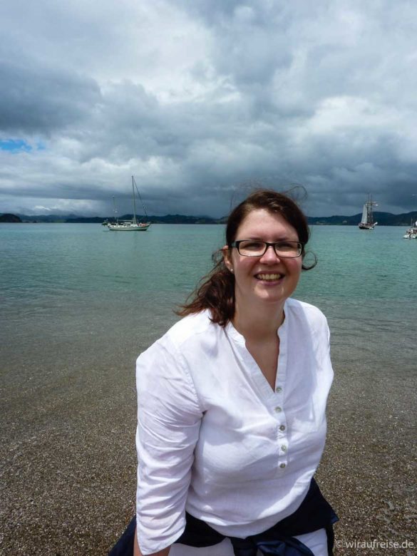 lachende Frau in weißer Bluse am Ufer - bay of islands neuseeland nordinsel